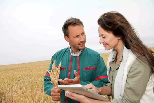 Femme avec une tablette discutant avec un agriculteur
